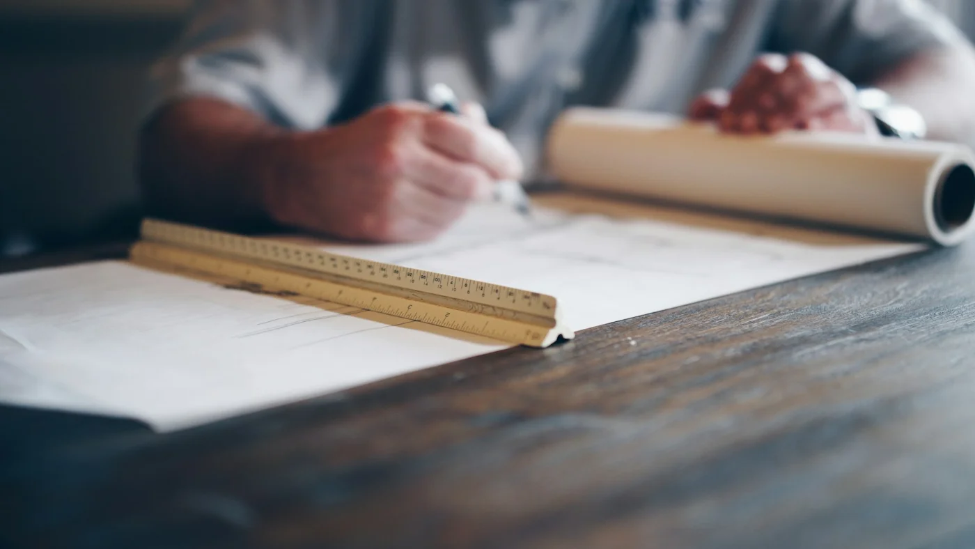 Revisión de planos y dibujo técnico sobre una mesa. Fotografía referencial.