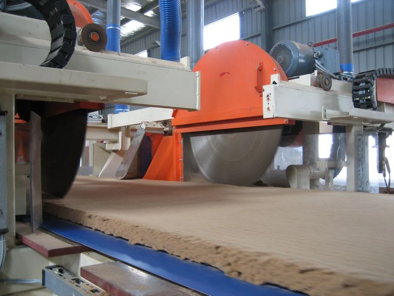 Fotografía referencial: manta de fibra de madera pasando por sierras de recorte en la fabricación de tableros MDF.